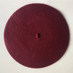 Flat lay macro view of a burgundy wool beret with detailed soft texture and top knot