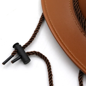 Detail of the brown leather cowboy hat featuring stitching and adjustable chin strap