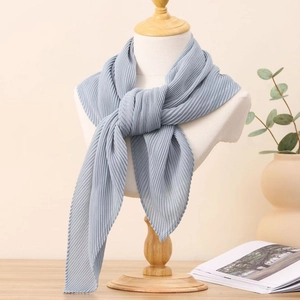 Détail d'un foulard carré plissé bleu clair drapé sur un mannequin pour un look élégant