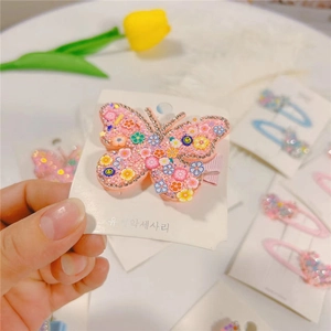 Detailed view of a pink butterfly hair clip with rhinestones and colorful smiling faces