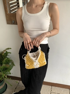 Close-up of yellow and white hand-woven bag with macrame pattern and drawstring lining