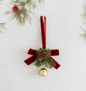 Close-up of a Christmas bow with velvet ribbon, pine cones, needles and golden bell