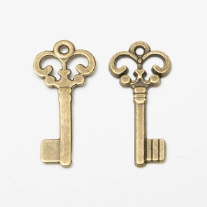 Pair of vintage bronze alloy key pendants for DIY jewelry making on white background