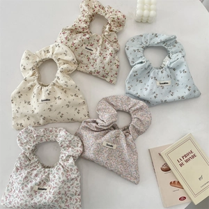 Flat lay of five floral cotton handbags with gathered scrunchie handles on a marble surface