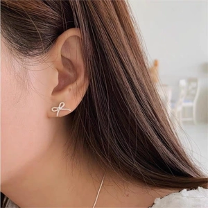 Detailed close-up of a 925 sterling silver bow earring with fine zircon inlay worn on ear