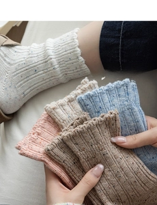 Detailed knit texture of wool blend socks with colorful speckles and ruffled edges