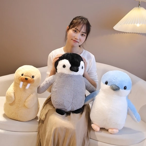 Plush penguin and walrus soft toys held by a model in a cozy home setting