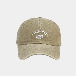 Detail of embroidered California 1987 logo on washed khaki cotton baseball cap