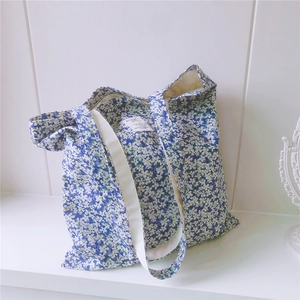 Close-up of blue floral cotton tote bag with white small flowers and woven shoulder strap