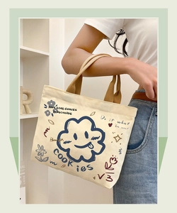Detail of canvas tote bag featuring cute blue cloud graphics and a cream fabric handle