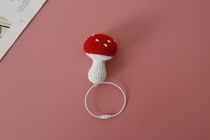Macro shot of handcrafted crochet mushroom charm with red cap and steel wire ring