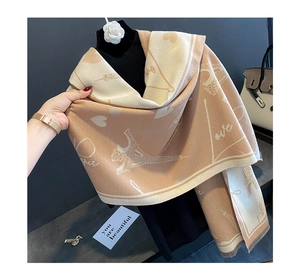 Close-up of beige cashmere scarf with Eiffel Tower pattern and Paris lettering