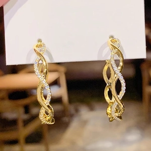 Close-up of golden wave hoop earrings with pavé set cubic zirconia on card