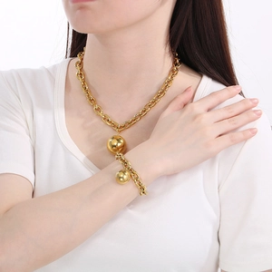 Close-up of chunky gold stainless steel chain necklace set with large ball pendants on model