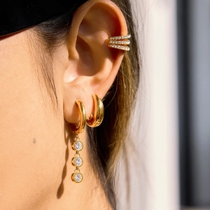 Polished 18K gold earrings set with zircon tassels and triple layer cuff on ear