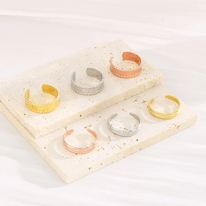 Detail of adjustable C-shaped rings in gold, silver, and rose gold on a stone base
