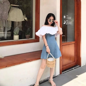 Detail of blue denim dress with white puff sleeves and woven pearl handle handbag