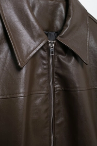 Close-up of dark brown leather bomber jacket collar and silver metal zipper texture