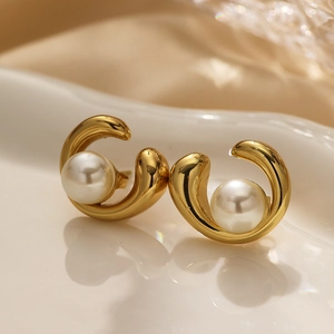 Detailed view of gold plated C-shaped earrings featuring a large lustrous white pearl