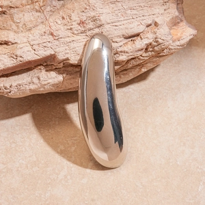 Macro shot of silver droplet brooch with high-polish finish on natural stone background