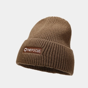 Close-up of thick brown ribbed knit beanie with 'THE FOCUS' embroidered patch detail