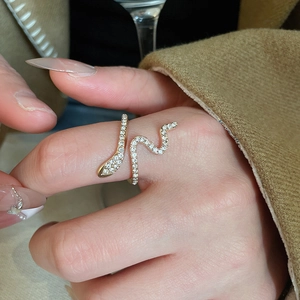 Detailed close-up of a gold snake-shaped ring with pavé crystals on a model finger