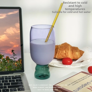 Creative purple and green contrast glass cup with yellow straw on an office desktop