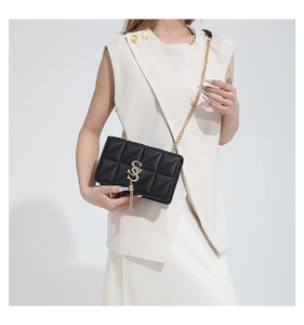 Detail of black quilted leather shoulder bag with gold S-logo and chain strap