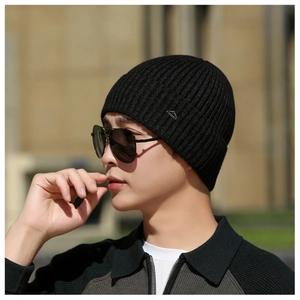 Detail of men's black knit beanie featuring a silver mountain logo and ribbed texture