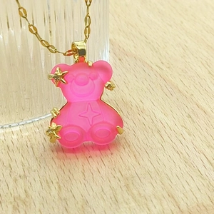 Close-up of pink resin bear pendant with gold star motifs on a thin water wave chain