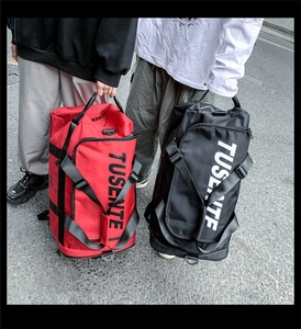 Detail of large Oxford travel bags in red and black with TUSENTE letter print and handles