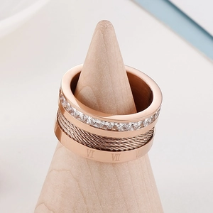Detail of rose gold cable ring with Roman numerals and square cut zircon on wooden stand