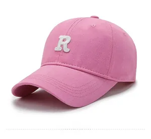 Close-up of pink cotton baseball cap with white embroidered R letter and curved brim