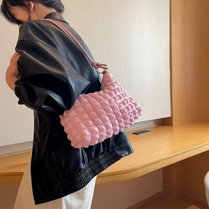 Dettaglio della trama a bolle rosa su una borsa a spalla morbida a pieghe con metallo