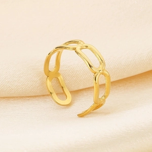 Detail of golden hollow chain ring on silk fabric highlighting metal texture