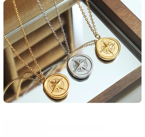 Detail of compass pendant necklaces in gold and silver finish with seal design