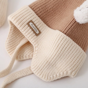 Detailed knit texture and brown First Day leather patch on a children's winter earflap hat
