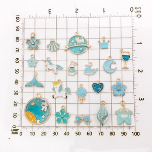 Blue enamel charms collection with gold trim displayed on a measuring grid for size scale