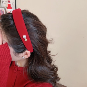Detail of red velvet headband with large pearl and gold tag on an elegant model