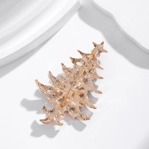 Golden Christmas tree brooch pin with secure metal safety pin clasp on stone background
