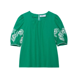 Haut vert en lin à manches bouffantes et broderie florale blanche sur fond blanc pur