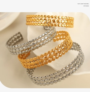 Detailed macro shot of stacked gold and silver bohemian style cuff bracelets in a ceramic tray