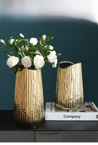 Detail of gold electroplated ceramic vases with vertical stripe texture and white roses
