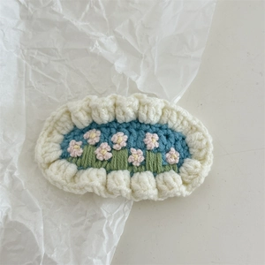 Detailed macro view of handmade crochet flower hairpin with light blue embroidery work