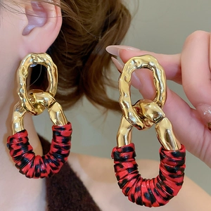 Detail view of large geometric chain drop earrings with hammered gold and leopard print