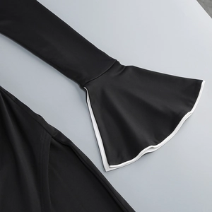 Detail of flare bell sleeves with white contrast piping on a black knit evening dress