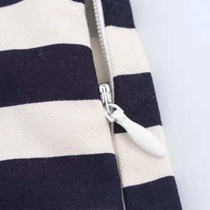 Detailed macro view of white invisible zipper on navy and white striped canvas shorts