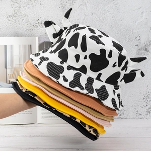 Cute cow print bucket hats with small horns and assorted colors in a stacked display