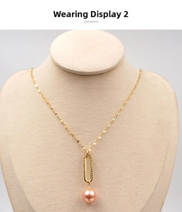Detail of golden oval textured link with pink pearl pendant on a neck mannequin