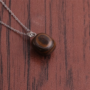 Detailed close-up of a silver chain necklace featuring a brown tiger eye gemstone pendant